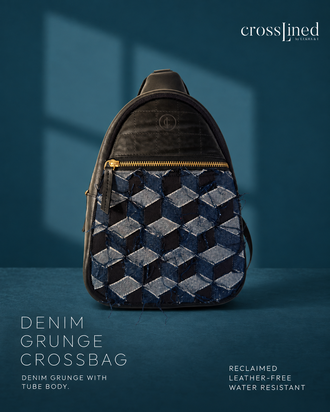 A Cross Lined crossbody bag made from reclaimed denim grunge, featuring a geometric 3D cube pattern in shades of blue and gray, with a black tyre tube top and gold zipper. The bag is displayed against a dark teal-blue background with soft window shadows.