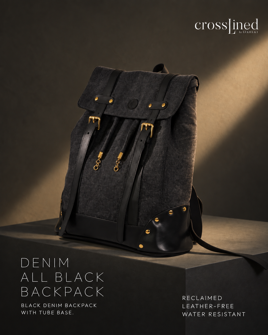 A black denim backpack with tyre tube straps and gold-tone hardware, displayed on a dark pedestal in a studio setting with dramatic lighting. The brand name 'crosslined' is visible in the top right corner.