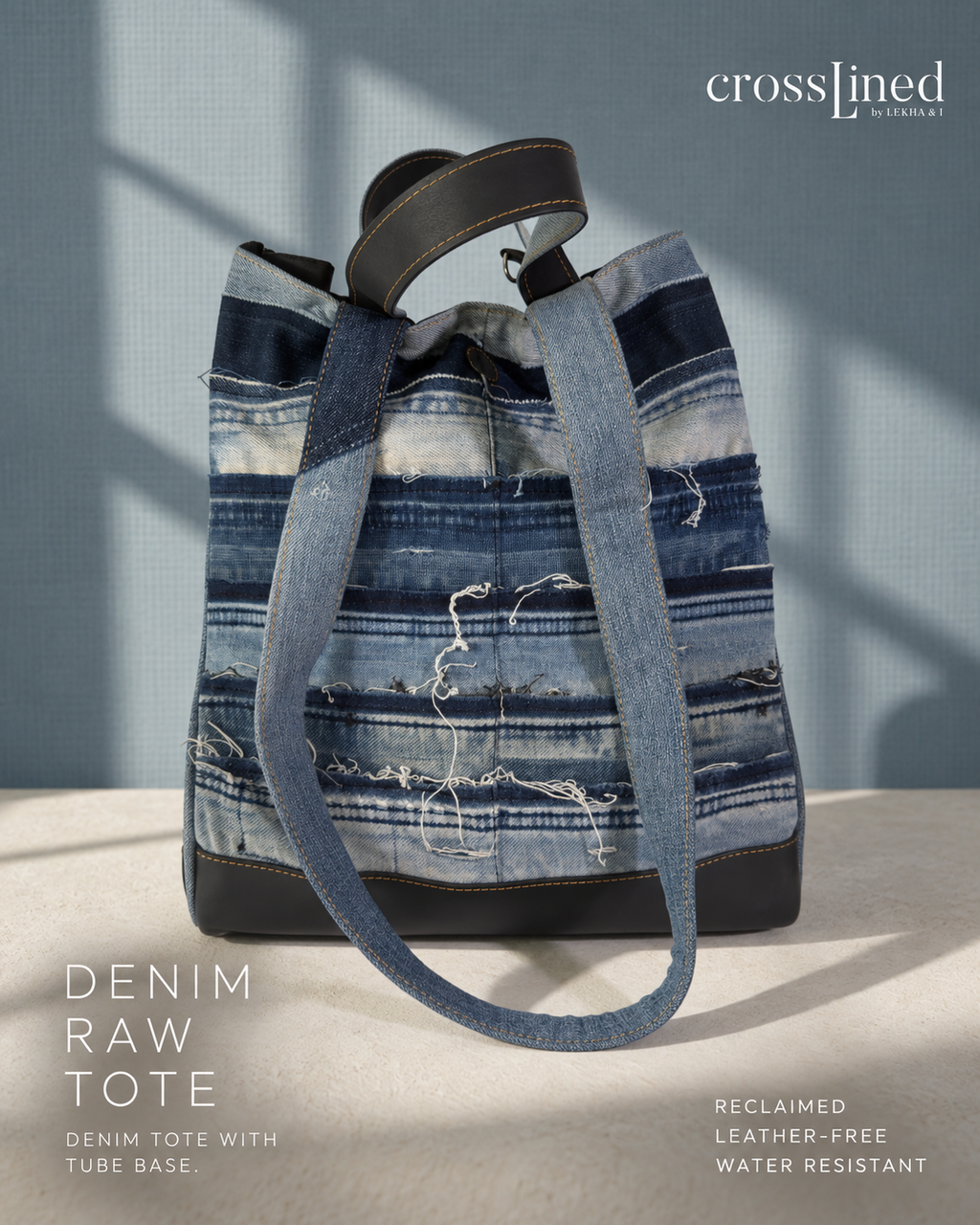 A Crosslined  'Denim Raw Tote' made from reclaimed blue denim strips with distressed frayed details, featuring a black tyre tube base and dual shoulder straps, set against a textured blue-gray background with soft window shadow overlays.