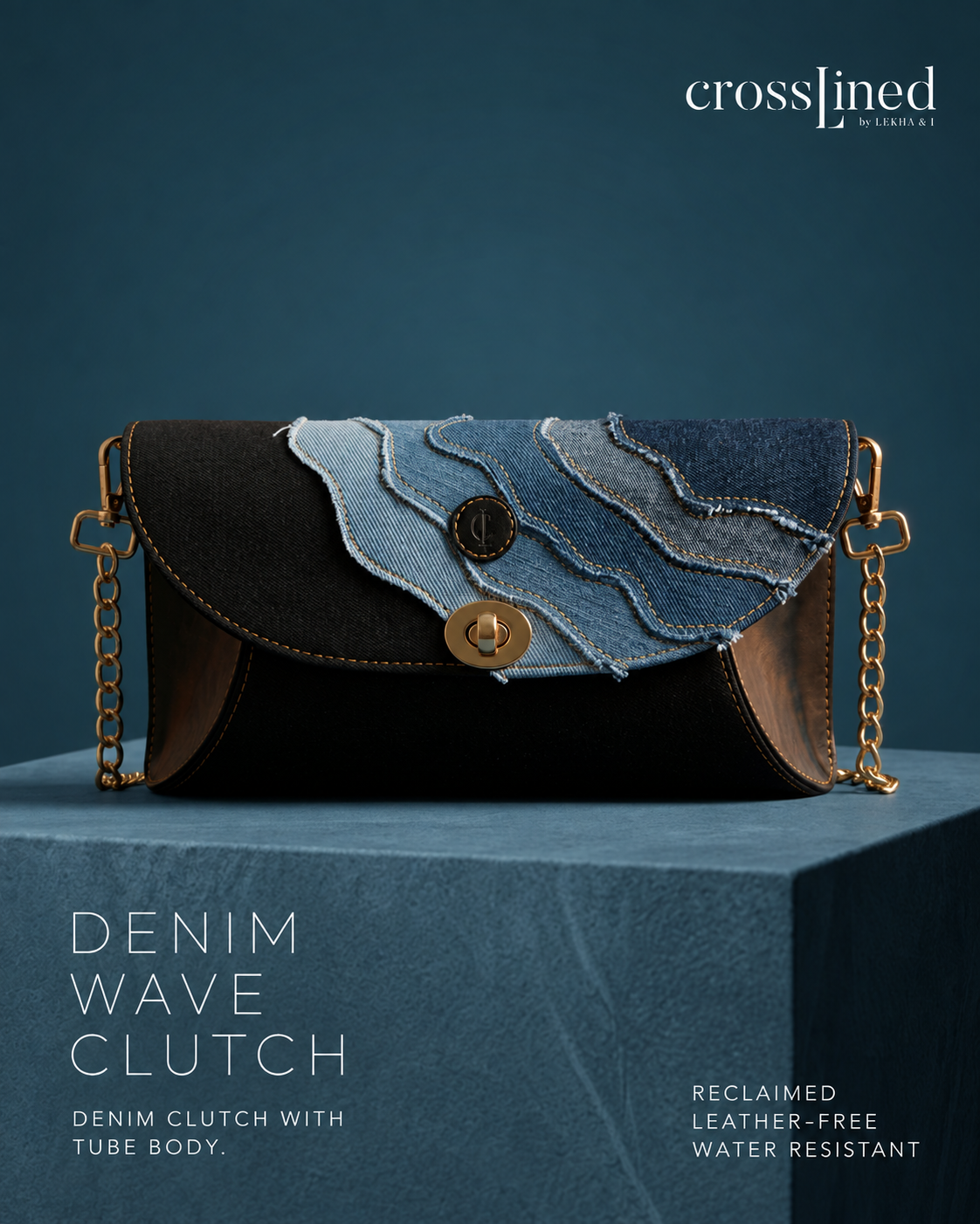 A Crossjined clutch bag with a black tube body, a flap made of layered denim in light and medium blue washes, and gold-tone chain straps, displayed on a blue pedestal against a dark blue background.