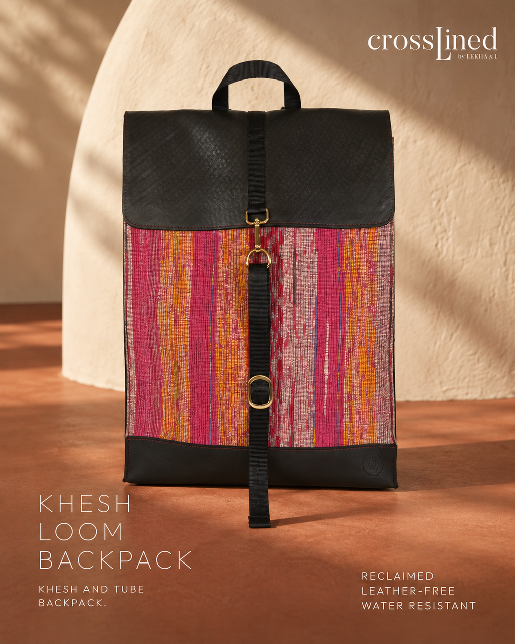 A CrossLined  Khesh Loom Backpack featuring a textured black top flap and base, with a central panel of vertical stripes in pink, orange, and red, displayed on a warm brown surface against a beige arch background.
