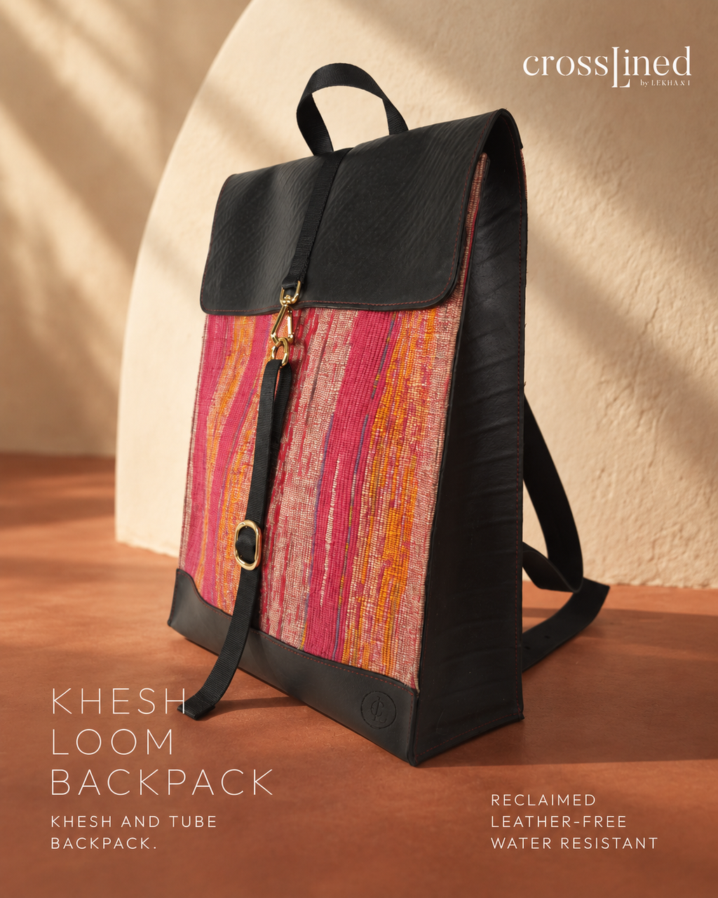 A CrossLined backpack made from reclaimed tyre tube and Khesh fabric, featuring a black top flap and base with a vibrant pink, orange, and red striped patterned front panel, shown on a wooden surface with a textured beige background.