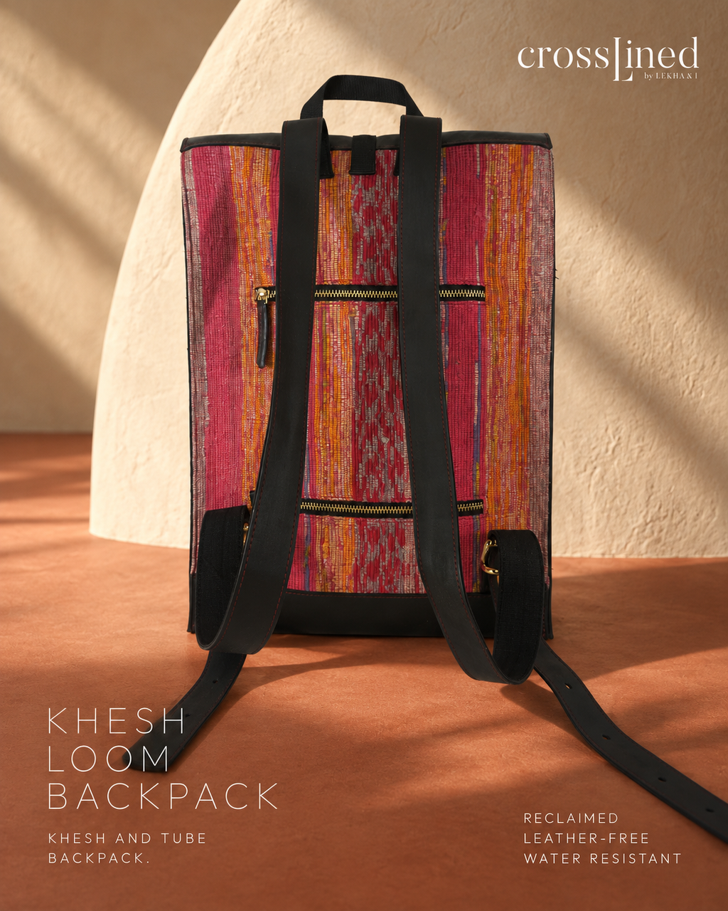 A Crosslined Backpack featuring a vibrant pink, orange, and yellow patterned Khesh fabric body with black straps and trim, set against a warm beige textured background with text overlays.