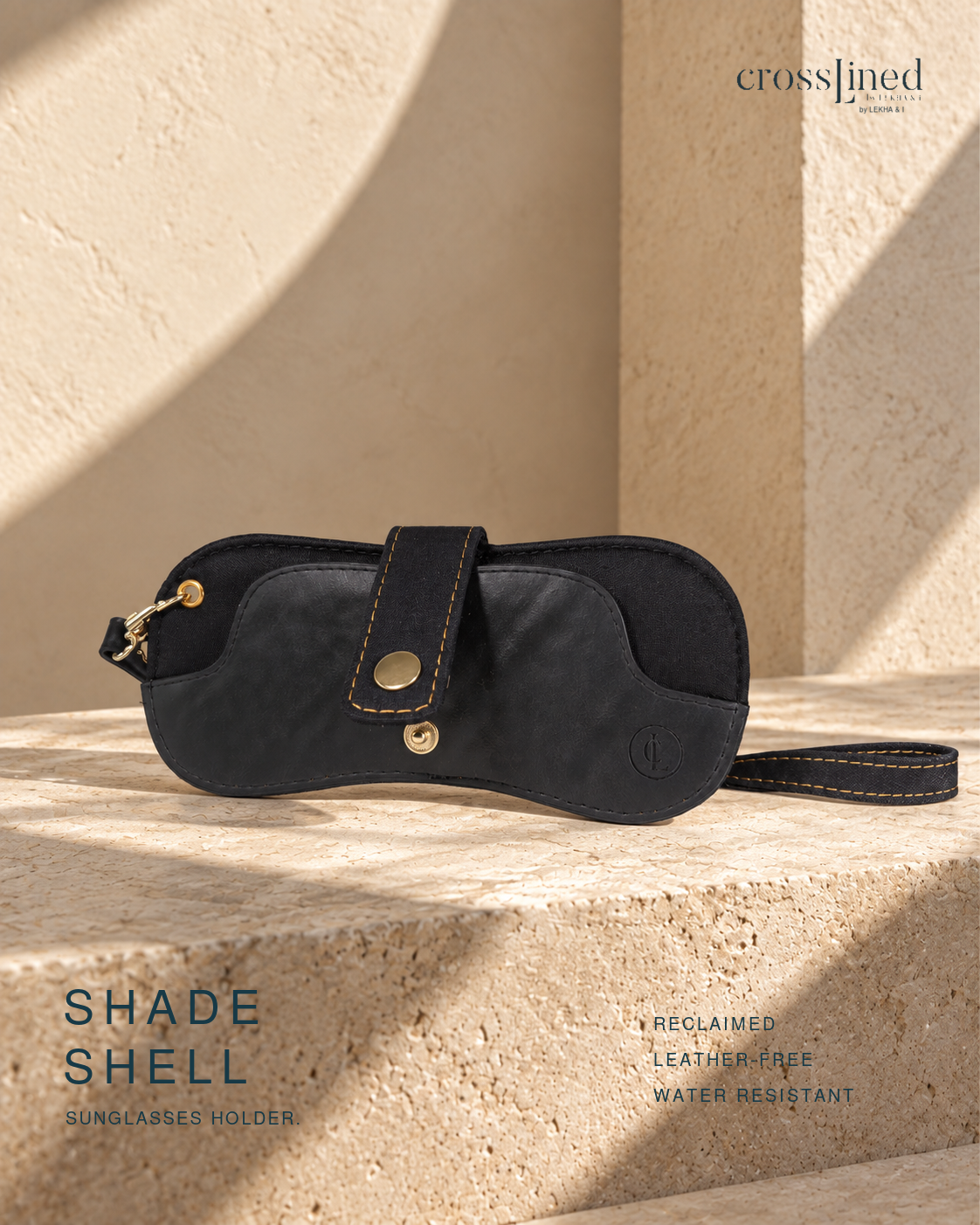 A black crossjined sunglasses holder shade shell with gold-tone hardware, displayed on a textured beige stone surface with dramatic shadows. The brand name 'crossjined' is visible in the top right, and 'SHADE SHELL' is written on the bottom left.